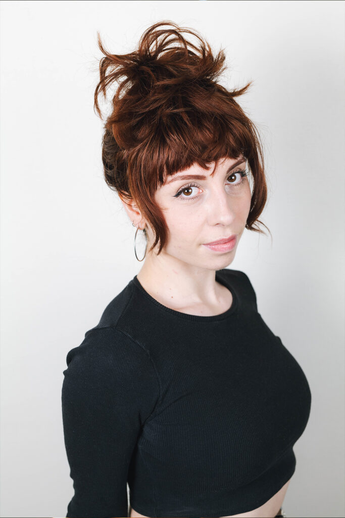 Portrait d'une comédienne aux cheveux roux attachés, vêtue d'un crop top noir, style naturel, photo book professionnel.