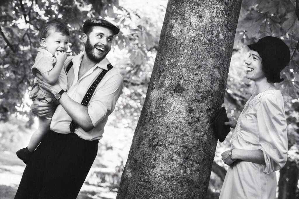 portrait d'un couple et leur jeune fils qui joue à cache-cache autour d'un arbre dans les bois