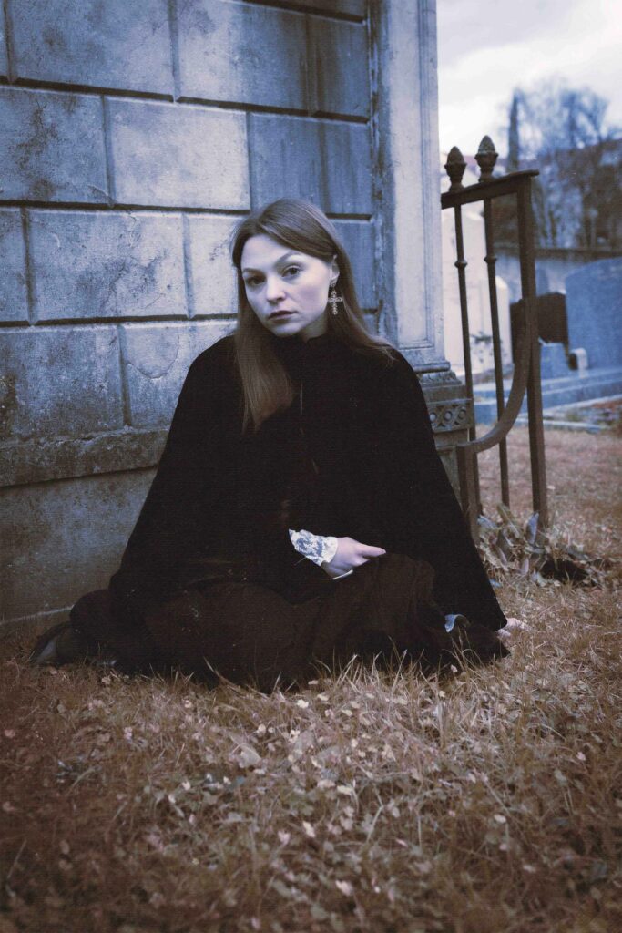 portrait d'une jeune femme gothique dans un cimetière, elle regarde l'objectif
