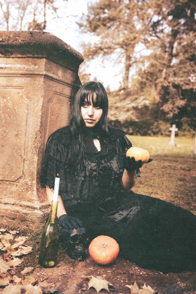 portrait vintage et nostalgique d'une femme assise, habillée avec une robe noire et portant une citrouille, ambiance halloween