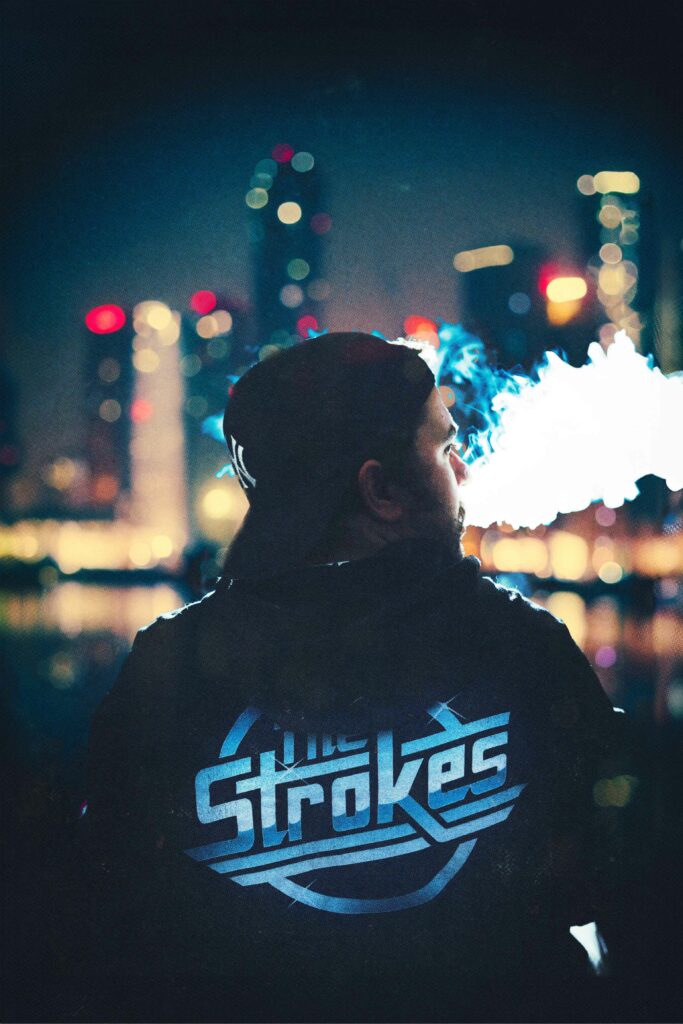Portrait de dos d'un homme en hoodie 'The Strokes', de la fumée sort de sa bouche, avec une ville illuminée en arrière-plan.