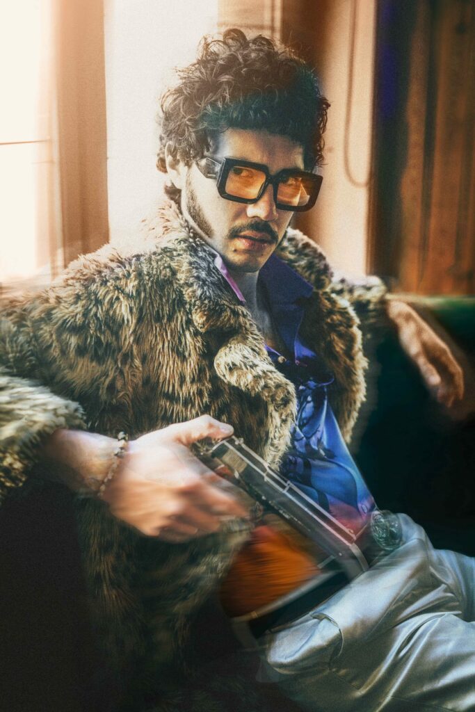 Portrait vintage d’un homme habillé d’un manteau léopard et de grosses lunettes à verres orangés, tenant un revolver dans la main droite, ambiance années 70 entre psychédélisme et mafia américaine.